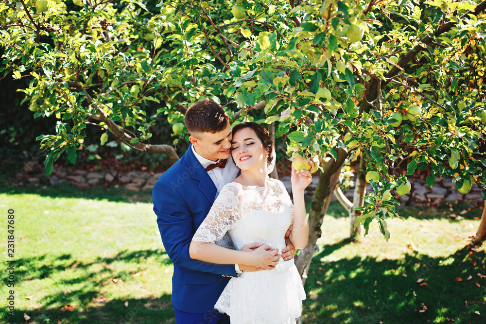 Just married loving hipster couple in wedding dress and suit in the park. Happy bride and groom walking in the beautiful garden. Romantic Married young family. Just married loving hipster couple in wedding dress and suit in the park. Happy bride and groom walking in the beautiful garden. Romantic Married young family.