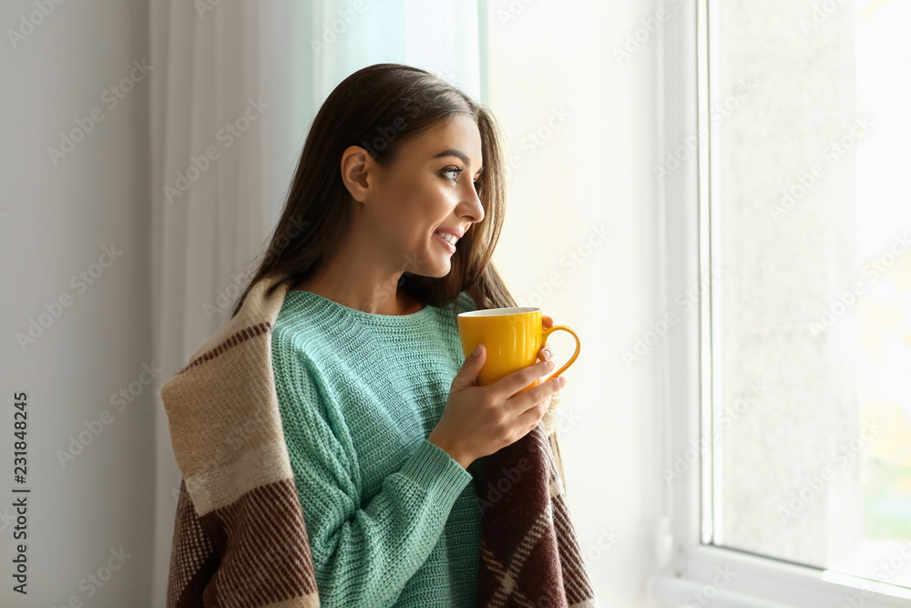Woman drinking tea near window on autumn day Woman drinking tea near window on autumn day
