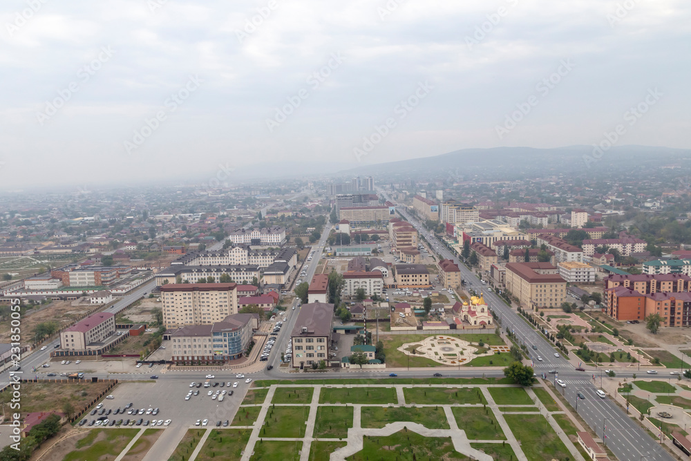 Grozny, Russia: 10.07.2015. Daily life in Chechen Republic. Aerieal view of the Akhmat Kadyrov Avenue, Orthodox Church of St. Michael the Archangel, multistorey buildings and mountains