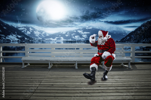 Red old Santa Claus and winter night. Landscape of mountains and lake. Free space for your decoration. Moon light . 