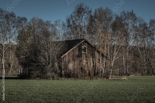 Abandoned barn standing overgrown on green field