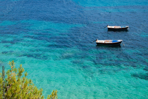 Two boats at rest in shallow water. Crystal clear turquoise waters of the Adriatic sea. Eastern bank of the famous Zlatni Rat (Golden Horn) beach in Bol on Brac island, Dalmatia, Croatia.