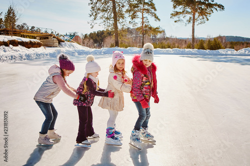 Four little happy girls are skating. They have fun with friends.