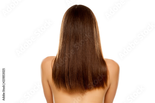 Back view of young nude woman with straight long hair on white background