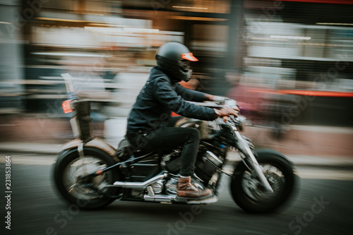 Blurry motion of man riding a motorcycle in the street.