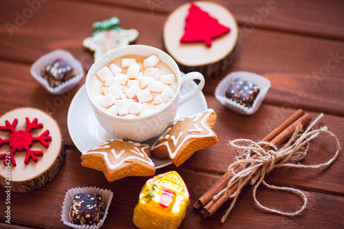 Cup of chocolate with marshmallow, gingerbread cookies, gifts and beautiful Christmas decorations on the wooden background. Flat lay, top view, space for a text.