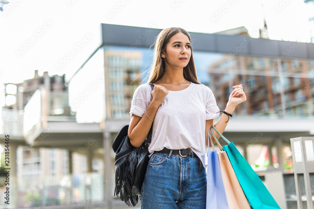 Young happy woman with shopping bags walking on street. Sale time. Young happy woman with shopping bags walking on street. Sale time.