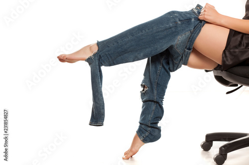 Slika na platnu Young woman trying to put on her tihgt jeans on white background