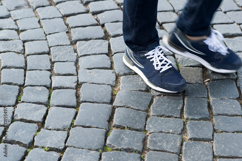 Legs in modern blue sneakers on the antique pavement. Start a new step