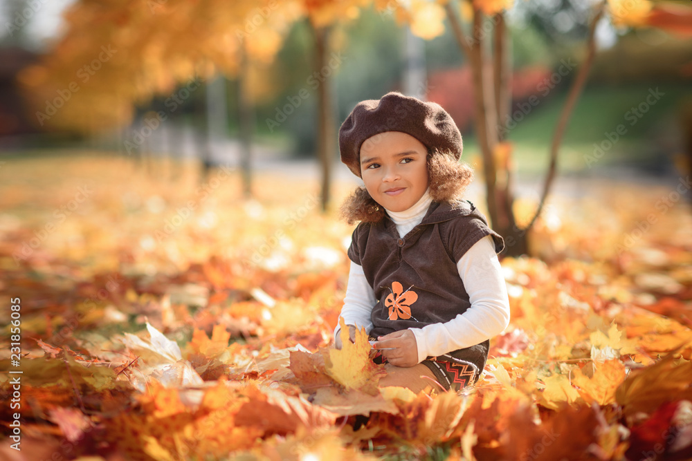 Charming little girl in a red dress sitting on a wood. chair in the autumn Charming little girl in a red dress sitting on a wood. chair in the autumn