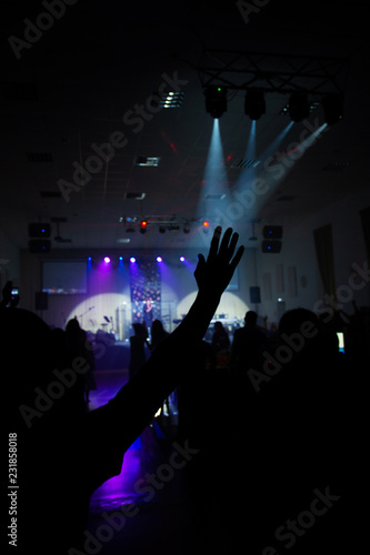 raised hands in a dark concert hall against the background of the stage