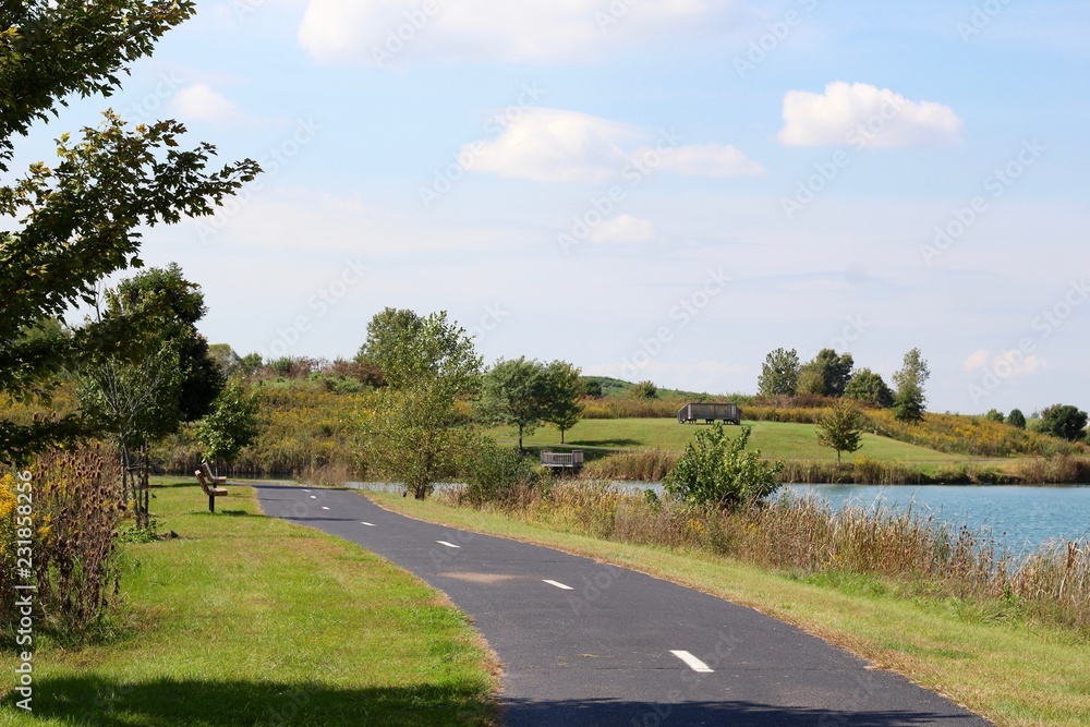 Fototapeta premium A long empty path along side of the water in the park.