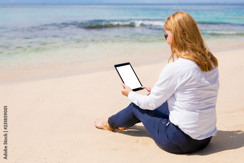 Business woman using tablet computer on the beach