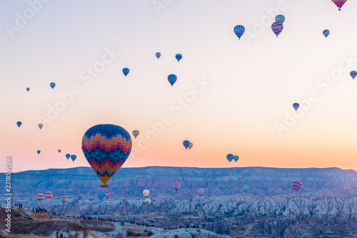 Many huge balloons are flying in the air at the sunrise. Beautiful morning view in Cappadocia, Turkey. Entertainment and new experience for tourists. 