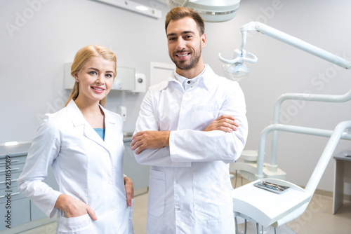 young male and female dentists looking at camera in dental office