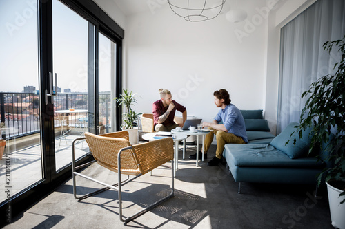 Two handsome casual businessmen working together at modern co-working space.