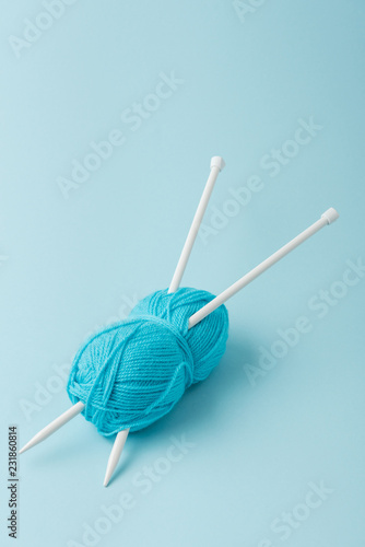 close up view of blue yarn clew and knitting needles on blue background