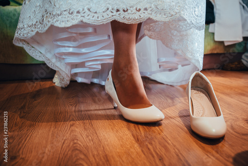 Bride puts on wedding shoes on her tender feet