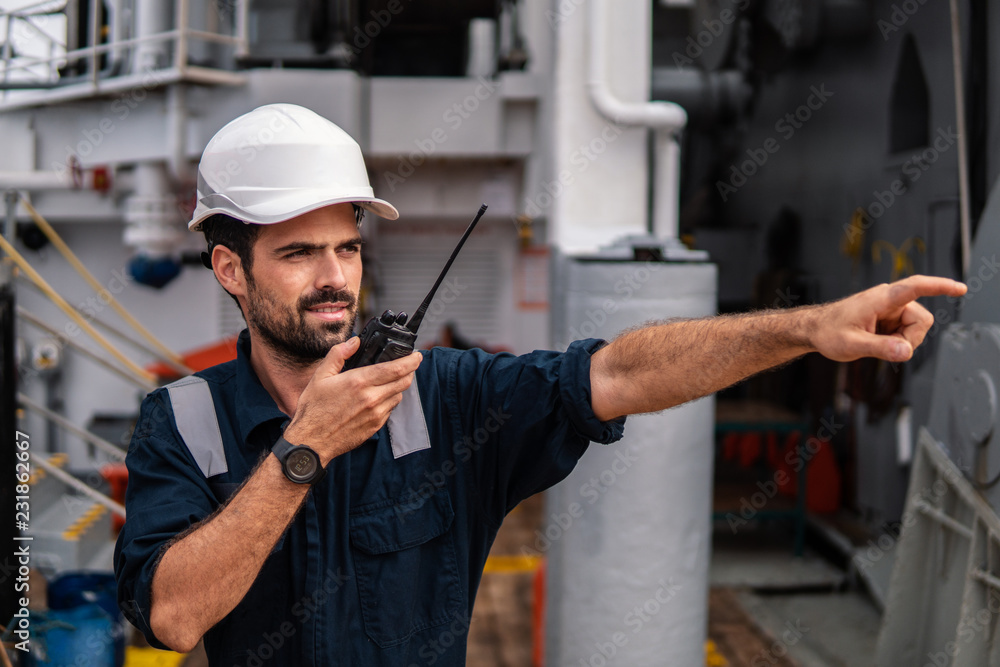 Marine Deck Officer or Chief mate on deck of vessel or ship . He holds VHF walkie-talkie radio in hands. Ship communication Marine Deck Officer or Chief mate on deck of vessel or ship . He holds VHF walkie-talkie radio in hands. Ship communication