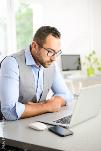 portrait of handsome trendy casual mid age business man in office desk with laptop computer