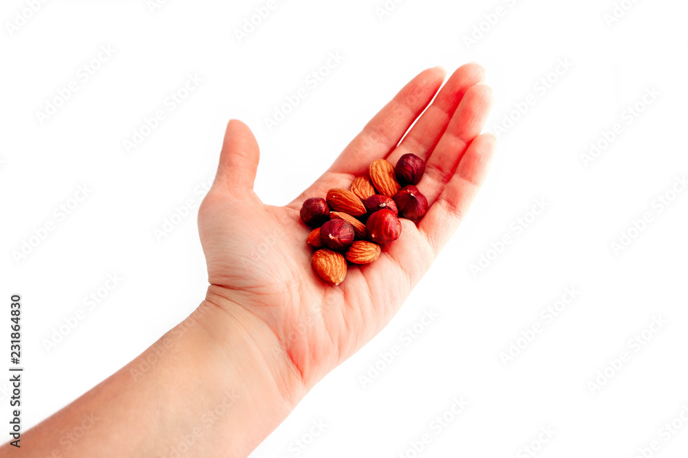 A pile of hazelnuts and almonds mixed, hold in a hand, isolated on white background. A pile of hazelnuts and almonds mixed, hold in a hand, isolated on white background.