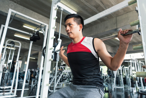 Young asian man lifting barbell in gym. healthy lifestyle and workout motivation concept.
