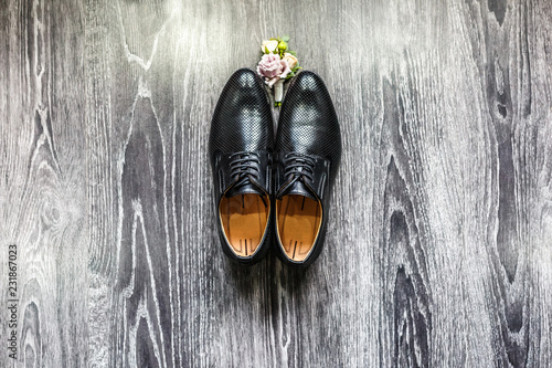 black groom's shoes with boutonniere on the parquet floor