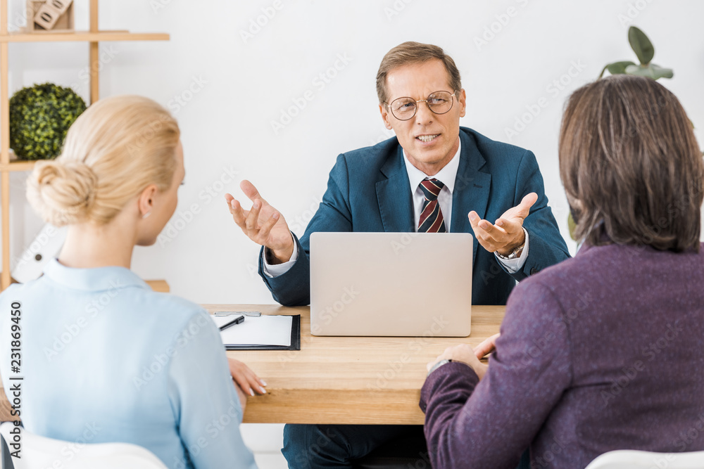 adult insurance agent in glasses talking to young couple in office adult insurance agent in glasses talking to young couple in office