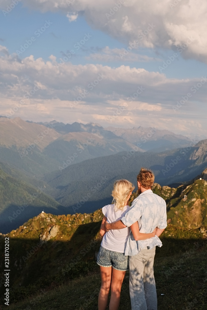 View of a couple watching the sunset on a meadow and the Mountain