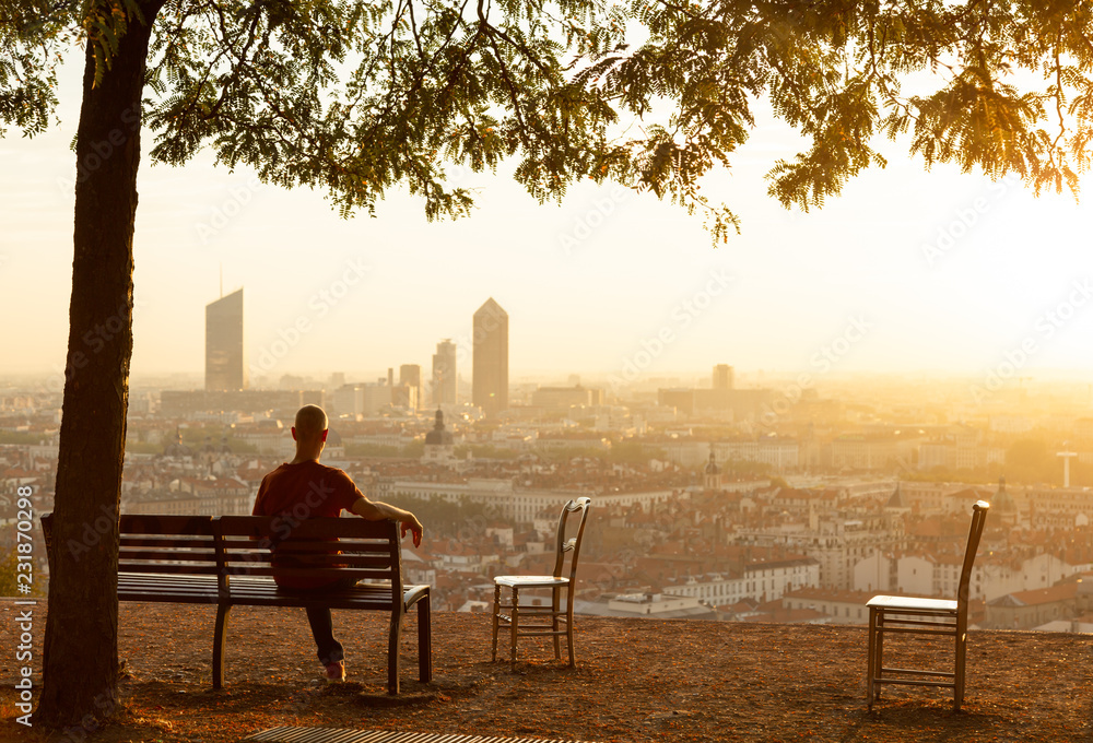Φωτογραφία Man on a bench enjoying the summer sunrise over the city of Lyon, France