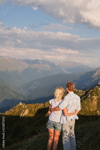 View of a couple watching the sunset on a meadow and the Mountain