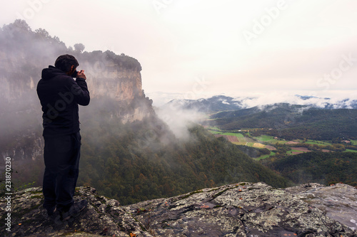 man taking a photo of a valley from the cliff