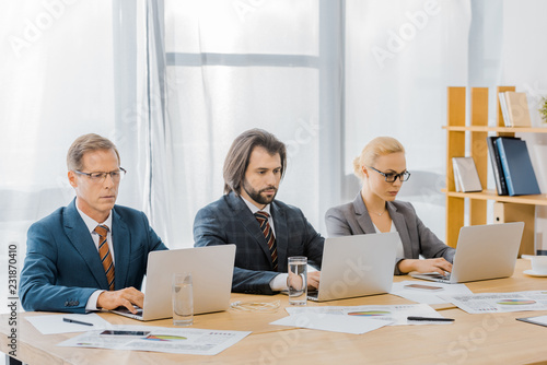 insurance workers sitting at table and using laptops in office