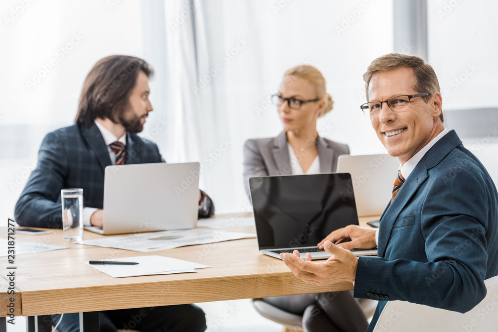 office workers sitting at table with laptops at meeting office workers sitting at table with laptops at meeting