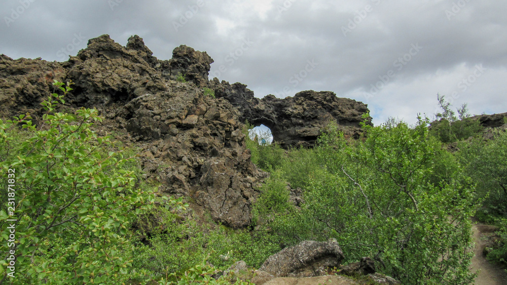 Dark lava rock formations area and green Icelandic forest in Myvatn area, Northern Iceland, Europe. Dark lava rock formations area and green Icelandic forest in Myvatn area, Northern Iceland, Europe.