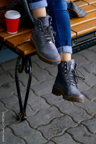 Woman siting on bench in gray boots