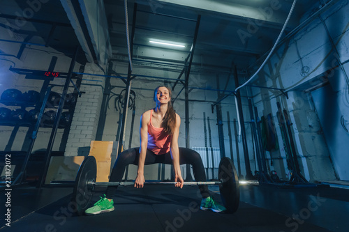 Athletic woman exercising with a barbell in the gym photo