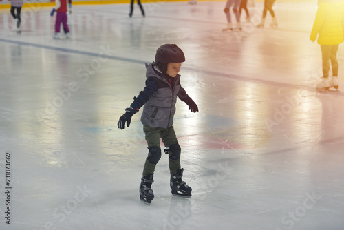 Adorable little boy in winter clothes with protections skating on ice rink © Daniel CHETRONI