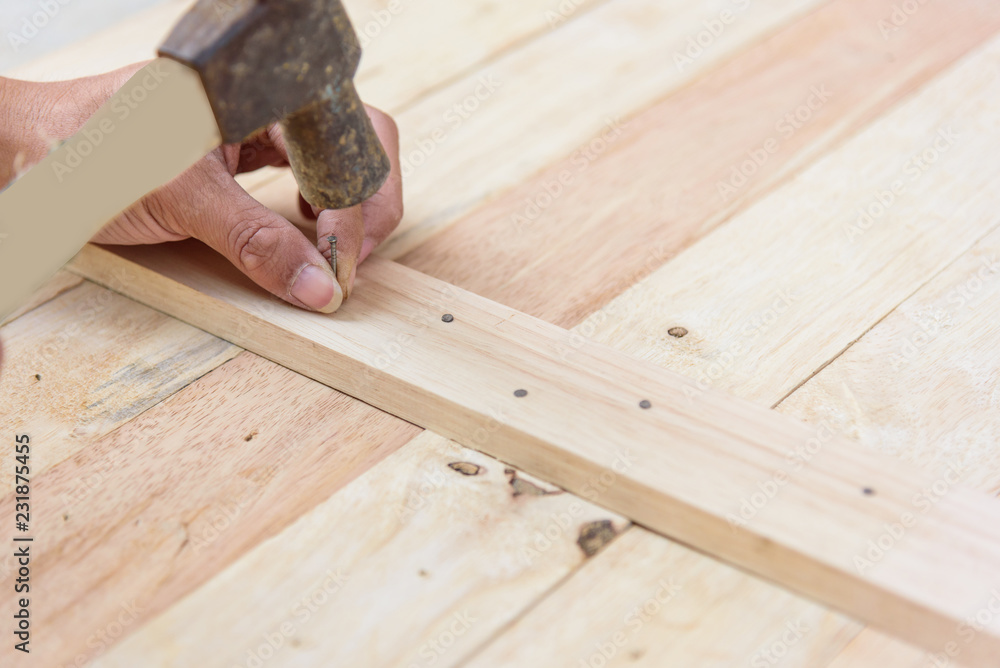 Worker hammer the nail into the wood Worker hammer the nail into the wood