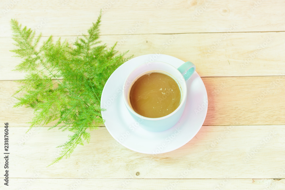 Obraz premium Hot coffee on wood plate with green leaf