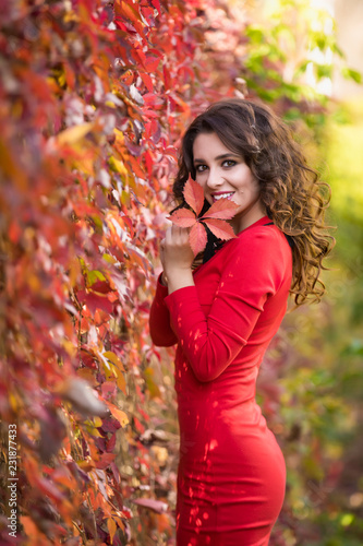 Beautiful young woman in red dress on a sunny autumn day