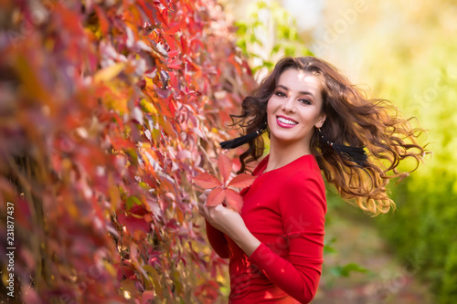 Beautiful young woman in red dress on a sunny autumn day