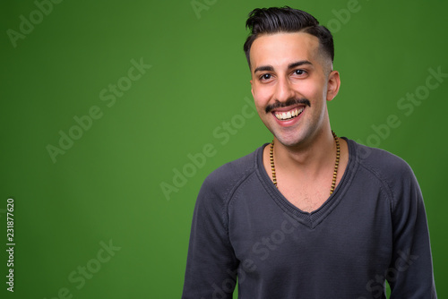 Young handsome Iranian man with mustache against green backgroun © Ranta Images