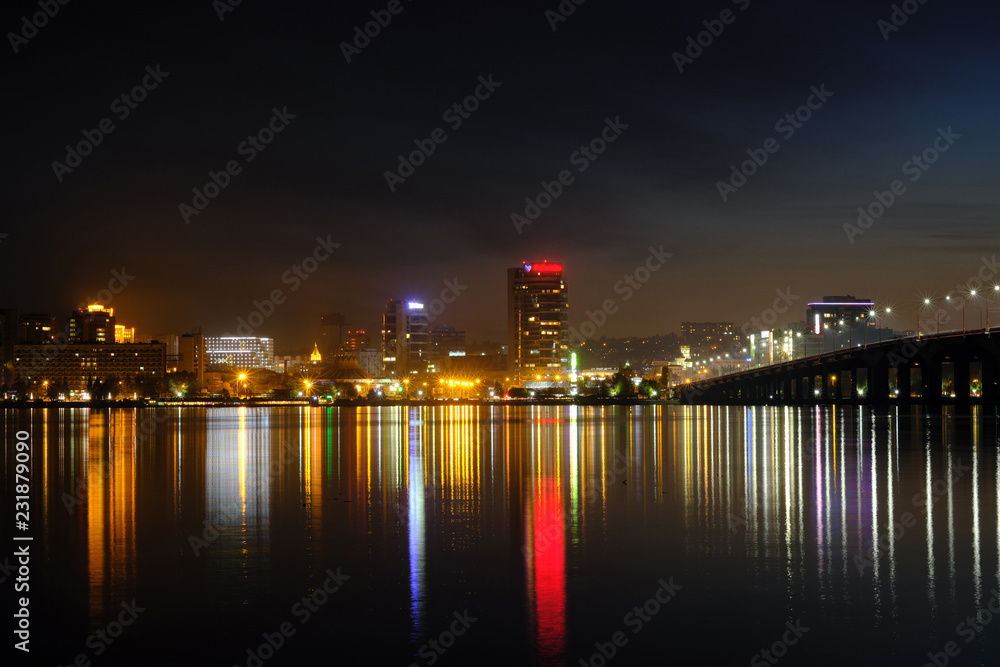 Panoramic view of the city at night. Cityscape near the river at night with reflection in the water.