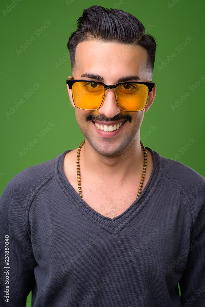 Young handsome Iranian man with mustache against green backgroun Young handsome Iranian man with mustache against green backgroun