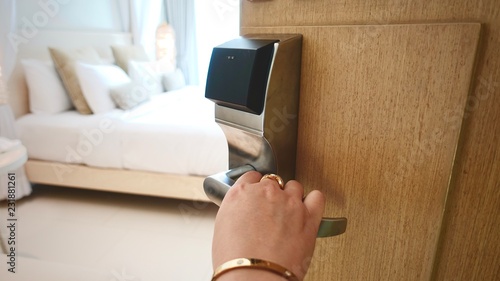 Female’s hand with accessories opening hotel room. Housekeeper or room service worker opening door to appartment.