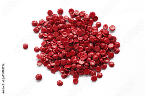 close up of red industrial plastic pellet on white background