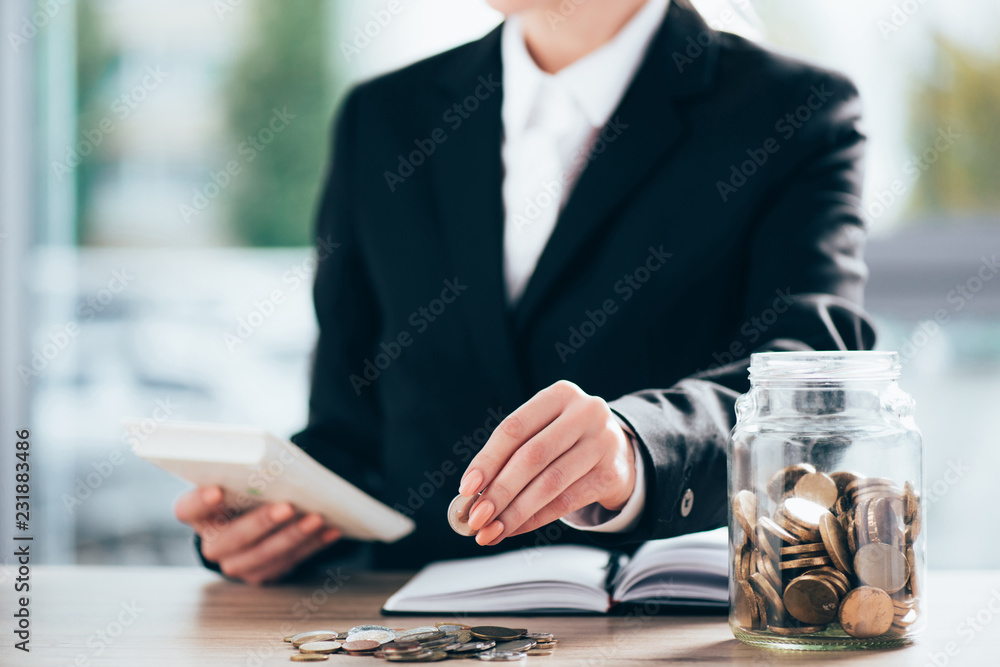 cropped shot of businesswoman working and putting coin on pile - obrazy, fototapety, plakaty 