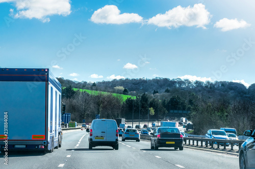 Closeup of busy Highway transportation motorway full of cars in the morning with dark cloudy blue sky and sunrise in beautiful spring nature