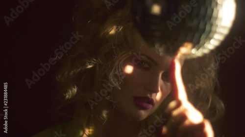 Woman spinning a disco ball on her finger with an enticing look, slow motion